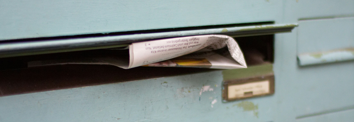 A newspaper sticking out of a letter box.